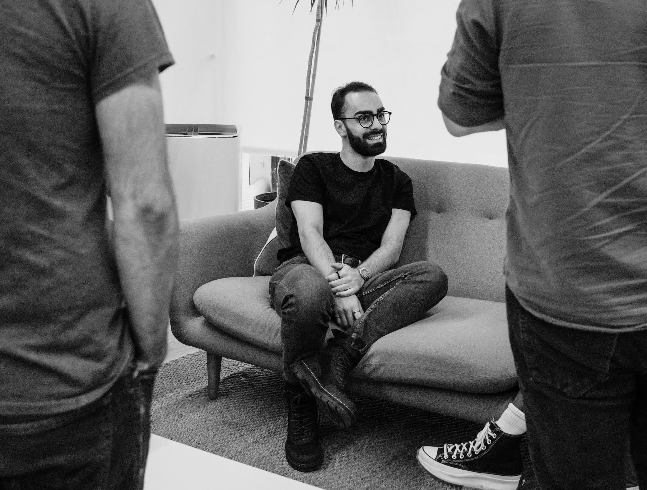 A person sitting on a couch smiling at his coworkers